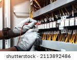 Small photo of Electricity and electrical maintenance service, Engineer using measuring equipment tool checking electric current voltage at circuit breaker terminal and cable wiring main power distribution board.