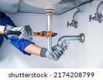 Small photo of Technician plumber using a wrench to repair a water pipe under the sink. Concept of maintenance, fix water plumbing leaks, replace the kitchen sink drain, cleaning clogged pipes is dirty or rusty.