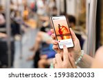 Woman riding in metro and viewing someone's photo on mobile phone.