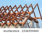 A timber roof truss, walls made of autoclaved aerated concrete blocks, a reinforced concrete beam and columns, a rough window opening, reinforced brick lintels, blue sky in the background