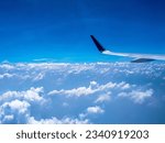 Small photo of A breathtaking capture of an airplane's left wing soaring gracefully above a sea of clouds and a vast expanse of clear blue sky. Embodies the thrill of flight and the vastness of the sky.