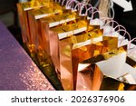 Small photo of A view of several golden goodie bags on a table, seen at a reception event.