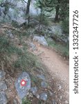 Small photo of A marked difficult mountain trail with large stones among green trees to Mirabela Fortress in Omis Croatia on a summer day. Concept trekking and hiking trips