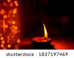 Happy Diwali background image of burning lit diya clay oil lamp with bokeh lights. Concept for Indian Hindu religious tradition, rituals festive season celebration at home.