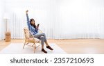 Small photo of Panorama View Shot of Young Asian Woman Relaxing in Modern Wicker Chair Near Window with Sheer Curtain, Happy Female Using Mobile Smartphone Enjoying at Home, Comfort and Cozy
