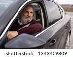 Handsome older man is driving his car and looking trough the window