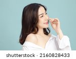 Beautiful short hair asian woman model touch her nose and clean fresh skin on blue background. Face care, Facial treatment, Cosmetology, beauty and spa, Women portrait.