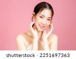 Small photo of Young Asian woman gathered in ponytail with natural makeup on face have plump lips and clean fresh skin wearing white camisole on isolated pink background. Portrait of cute female model in studio.