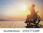 Small photo of Disabled person silhouette winners hand holding gold medal top of wheelchair have sunset background. International Disability Day and Handicapped Paralympics. Challenge, Conquer and healthcare concept