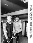 Small photo of personal trainer helping young man making pulley pushdown standing - tricep exercise - finish exercise - focus on the trainer face