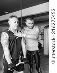 Small photo of personal trainer instructing young man making pulley pushdown standing - tricep exercise - finish exercise - focus on the trainer face