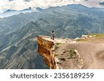 Small photo of Russia, Dagestan, 05.19.2023, the place of the old abandoned village of Goor. Mountain ranges, ravines, cliffs and abysses make up a wonderful extreme mountain landscape. On a stone ledge, which among