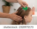 Small photo of A woman helps to get rid of lice and parasites on the head of a little girl, combs her head with a special comb. Treatment of lice and nits. High quality 4k footage