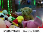 A soft lonely bear looks at the slot machine with soft toys with sadness.