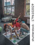 Small photo of Party activities. Three friends playing active twister game at the party