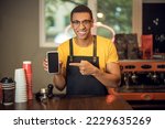 Small photo of Joyous cafe worker showing off his cellphone in the workplace