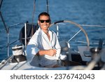 Contented man in sunglasses sitting on a yacht deck with a cup of coffee