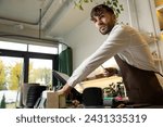 Small photo of Male barista at counter using cashbox computer in cafe store checking client's order