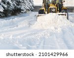 Close - up of snowplow plowing road during storm. Winter snow removal yellow large tractor. Removing snow in street after blizzard in Riga, Latvia
