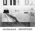 A bathroom with a white marble sink, thick bblack veins and black soap dispencer on top of the marble counter. high mirror and silver towel racks on the right hand side.