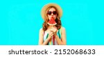 Small photo of Summer portrait of young woman with juicy lollipop or ice cream shaped slice of watermelon wearing straw hat, red heart shaped sunglasses on blue background, blank copy space for advertising text