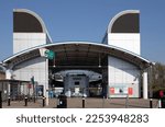 Small photo of London, UK - April 20 2021: The Island Gardens DLR station is at the south of the Isle of Dogs in London. This shows the main entrance on a clear, sunny day with just one or two people in the frame.