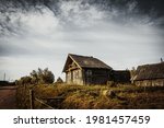 An old, abandoned log house. Deserted village in Russia. A lonely hut without people. Rotten wall construction. Hut against the background of the blue sky. Karelia. Russia. Day.