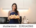 Portrait of young beautiful Asian woman making cupcake and showing cupcake to the camera  