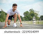Small photo of Handsome determined athletic young Asian man in sportswear preparing to run, steady starting position. Training, workout, exercise