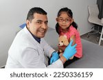 Small photo of Dark-haired Latino doctor and little girl have a medical consultation in the pediatric office to vaccinate their arm against Covid, chickenpox, diphtheria, influenza, hepatitis, measles, mumps