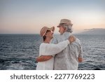 Small photo of Back view of romantic senior couple or pensioners embraced at the sea at sunset light expressing love and tenderness - old couple outdoors enjoying vacations together