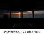 Small photo of Sunset over ocean seen from inside ship's bridge or wheelhouse. Sunlight reflecting from the ocean surface.