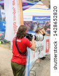 Small photo of A man in a red Canon shirt taking pictures with super telephoto lens. The lens is Canon 400mm.