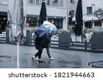 Small photo of Girls take shelter with umbrellas from light rain and strong wind outside in bad weather.