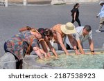 Small photo of Group of tourists looking cool in a fountain on a very hot day. Heat record in Italy. Rome 08.06.2022