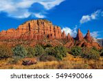  Arizona, Sedona, Cathedral Rock mountain range; in the Coconino National forest. Blue skies and billowing white clouds cover the enriched red oxide cliffs, and vast desert    landscape.