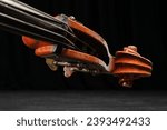 Small photo of Ancient brown double bass neck, double bass scroll and tuning pegs. Vintage contrabass head. Selective focus