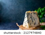 Small photo of Blue cheese, dor blue or roquefort mold cheese slice on cutting board with basil leaves, lifestyle food