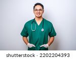 Small photo of Close-up of professional male doctor or nurse wearing green scrubs, holding hands in pockets and smiling broadly isolated over white background