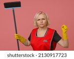 Small photo of angry maid in an apron and gloves brandishes a brush and threatens with a fist on a colored background