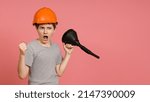 Small photo of fighting screaming boy in a gray t-shirt with a helmet on his head brandishes a big funnel and shows his fist, pink background with copy space