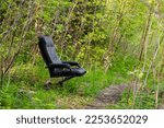 Small photo of A misplaced recliner chair by a forest path.