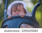 Small photo of Alingsas, Sweden - August 20 2021: Small child sitting in a Hags playground swing.