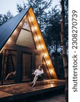 Small photo of A frame triangle holiday house in the woods at night, peaceful weekend getaway in nature