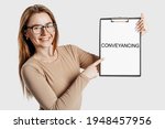 Small photo of Conveyancing. Beautiful young business woman wearing glasses holds a clipboard with mock up space isolated on gray background