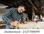 Small photo of Hispanic carpenter working in his workshop - man working with carpentry tools - happy carpenter working