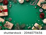 Christmas frame with gift boxes, holaday decorations and confetti on green background.
