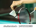 Hands of BADMINTON player holding racket serving white new shuttlecock with blur Badminton court background, popular indoor sport concept