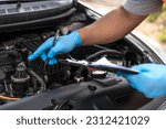 Close up mechanic man with blue rubber gloves checking car problem lists in auto repair garage, car mechanic check up and maintenance openhooded car 