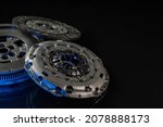 Small photo of New auto parts forming the clutch kit, pressure plate, disc clutch, placed on black material with blue tech light, negative space.